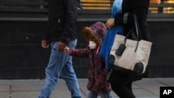 Seorang anak perempuan mengenakan masker saat berjalan bersama orang tuanya di pusat kota Teheran, Iran, 27 Februari 2020. 