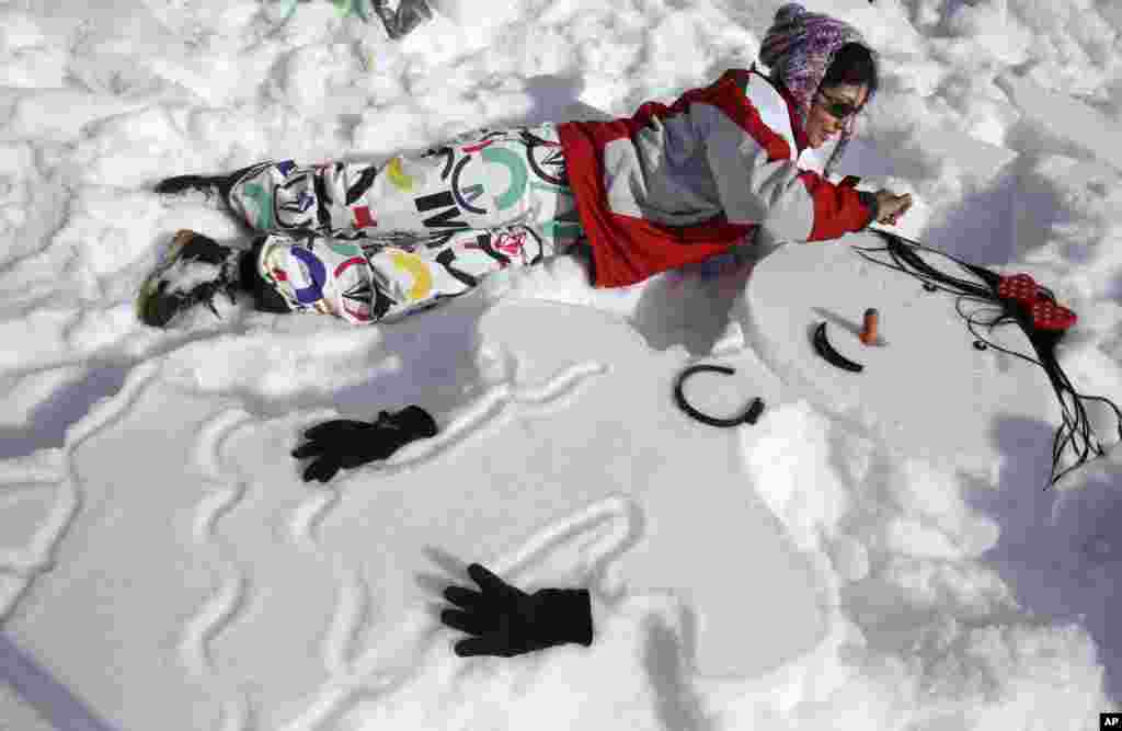 Seorang perempuan Iran membuat "snowwoman" pada kompetisi di Dizin di sebelah utara ibukota Iran, Tehran. Sekitar 600 warga Iran berpartisipasi dalam festival salju yang diselenggarakan oleh Federasi Ski Iran di resor ski Dizin.