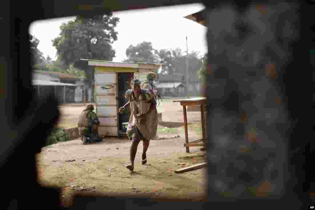 A woman runs for cover as heavy gunfire erupts in the Miskin district of Bangui, Central African Republic, Feb. 3, 2014.