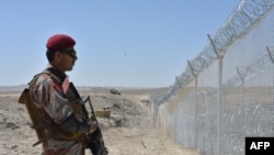 FILE- A Pakistani army soldier stands guard along with border fence at the Pakistan-Afghanistan border near the Punjpai area of Quetta in Balochistan on May 8, 2018.