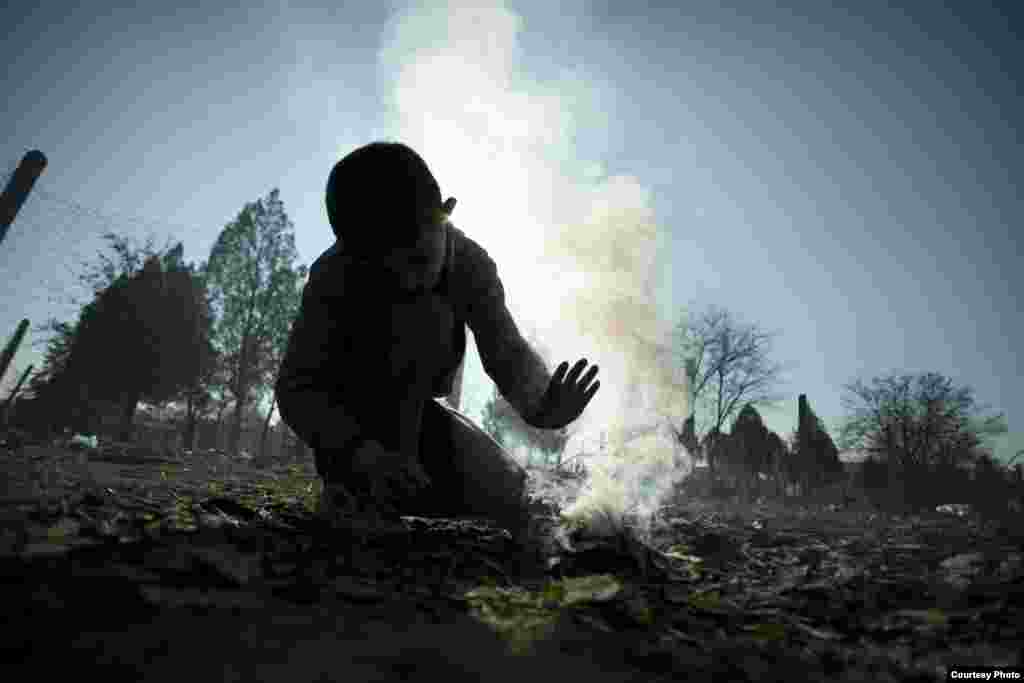 A boy tries to light a fire to warm himself at the refugee camp at Harmanli. UNHCR/D.Kashavelov