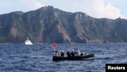 Sebuah perahu Penjaga Pantai Jepang (depan) dan kapal layar berisi sekitar 20 aktivis nasionalis dan nelayan Jepang berlayar ke kepulauan sengketa Senkaku di Timur Laut Cina (18/8).