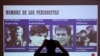 Un miembro de una organización de derechos humanos toma una fotografía de una pantalla que muestra a cuatro periodistas holandeses asesinados por las Fuerzas Armadas de El Salvador en el 39 aniversario del crimen, en San Salvador, el 17 de marzo de 2021.