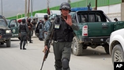 An Afghan policeman prevents journalists from approaching Cure International Hospital in Kabul, Afghanistan, April 24, 2014. 