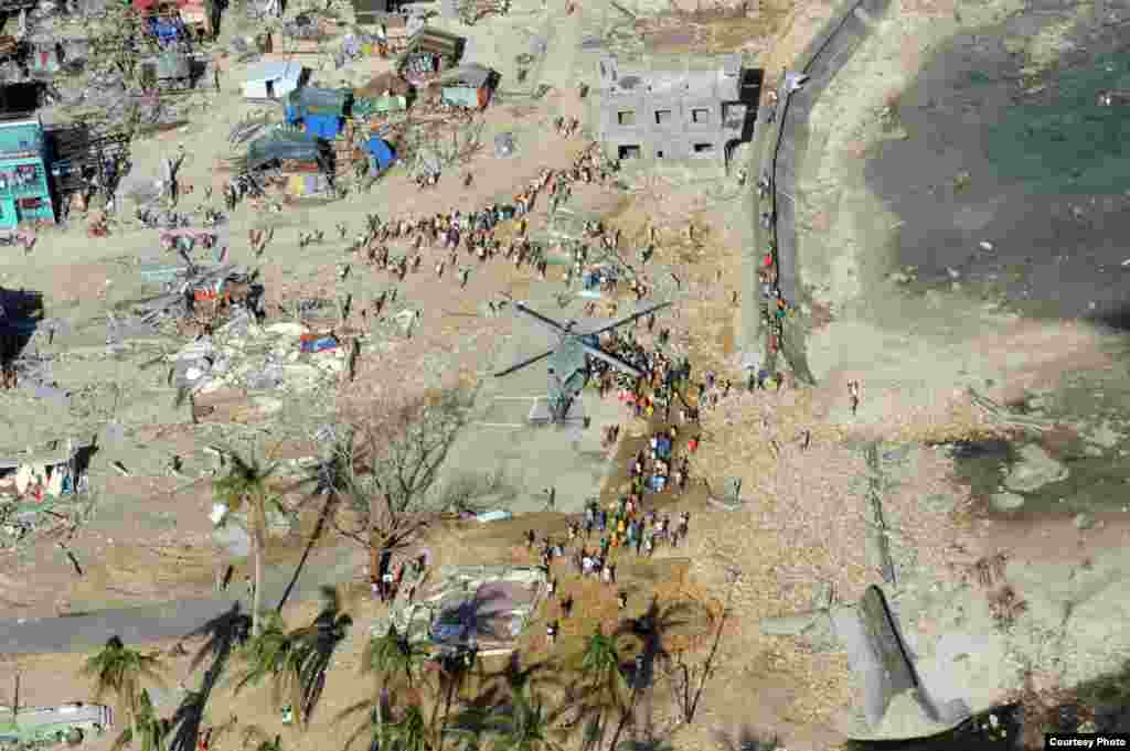 Philippine citizens gather around a MH-60S Seahawk as it delivers relief supplies. (U.S. Navy)