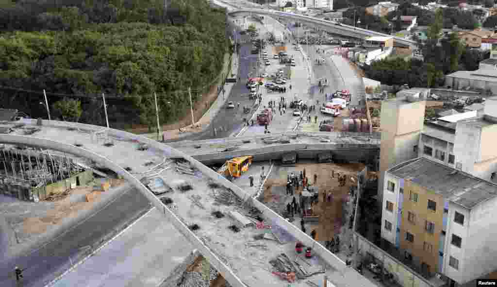 regu penolong berupaya menggapai kendaraan-kendaraan yang terperangkap di bawah jembatan ambruk yang masih dalam tahap pembangunan di Belo Horizonte (3/7).