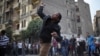 A protester throws stones at riot police during clashes at Tahrir square in Cairo, November 26, 2012.