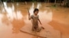 FILE - A girl uses a mattress as a raft during the flood after the Xe Pian-Xe Namnoy hydropower dam collapsed in Attapeu province, Laos, July 26, 2018.