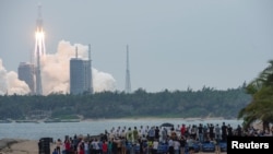Orang-orang menyaksikan dari pantai saat roket Long March-5B Y2, yang membawa modul inti stasiun luar angkasa China Tianhe, lepas landas dari Pusat Peluncuran Luar Angkasa Wenchang di Provinsi Hainan, China, 29 April 2021. (Foto: China Daily via REUTERS)