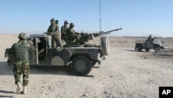 FILE - Afghan National Army soldiers stand guard at a checkpoint on the way to the Sangin district of Helmand province, Afghanistan, Dec. 23, 2015.