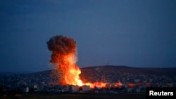 Asap dan api di atas kota Kobani akibat serangan udara, terlihat dari tempat penyeberangan perbatasan Turki-Suriah, Mursitpinar di kota Suruc, provinsi Sanliurfa, 18 Oktober 2014. 