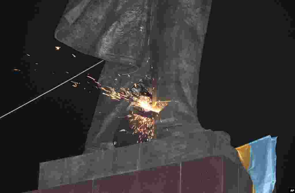 An activist cuts through the base of a monument to Vladimir Lenin at a pro-Ukraine rally in the central square of the eastern city of Kharkiv, Sept.28, 2014.