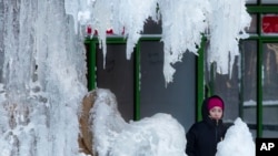 A woman passes an ice-covered fountain in New York's Bryant Park, Jan. 5, 2018. Frigid temperatures, some that could feel as cold as minus 30 degrees, moved across the East Coast on Friday as the region attempted to clean up from a massive winter storm. 