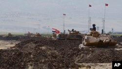 Serdadu Turki dan Irak duduk di atas tank-tank Turki saat latihan di Silopi, dekat pintu perbatasan Habur yang berbatasan dengan Irak, di tenggara Turki, Selasa, 26 September 2017 (DHA-Depo Photos via AP)