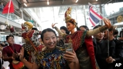 นักท่องเที่ยวจีนถ่ายรูปกับหุ่นละครเล็ก ที่สนามบินสุวรรณภูมิ เมื่อ 25 กันยายน 2023 (ที่มา: AP)