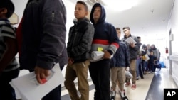 A line of migrants recently released by U.S. immigration authorities waits to check in at the Catholic Charities shelter in McAllen, Texas, Jan. 11, 2019.