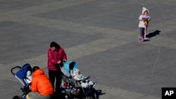 Sejunmlah warga tampak membawa bayinya ke sebuah taman di Beijing, China, pada 17 Februari 2019. (Foto: AP/Andy Wong)