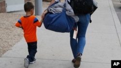 José, de tres años, originario de Honduras, es ayudado por una representante de Southern Poverty Law Center para que se reúna con su padre el martes, 10 de julio de 2018, en Phoenix, Arizona.