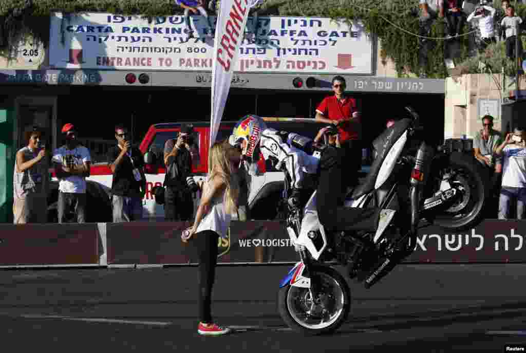 Pembalap Chris Pfeiffer melakukan aksi dengan sepeda motor BMW-nya sambil mencium seorang perempuan, selama 'road show' di kota Yerusalem.