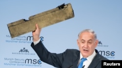 Le Premier ministre israélien Benjamin Netanyahu brandit une pièce d'un drone iranien qui aurait été abattu dans l'espace aérien israélien lors de son discours à la conférence de Munich sur la sécurité, en Allemagne, le 18 février 2018.