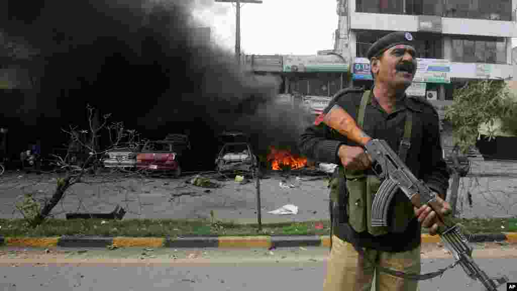 A Pakistani police officer stands guard at the site of a bombing in Lahore, Pakistan, Feb. 17, 2015.