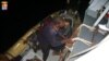 FILE - Refugees climbing aboard an Italian naval vessel near the Italian port of Pozzallo, south of Sicily. 