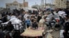 Seorang pria Palestina mengantar bantuan kemanusiaan dengan motor di tengah sejumlah warga Palestina yang juga berupaya mendapatkan bantuan di luar kantor UNRWA di Rafah, selatan Jalur Gaza, pada 3 Maret 2024. (Foto: AFP)