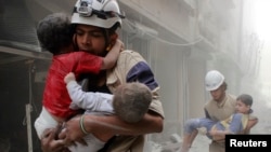 Miembros de la Defensa Civil rescatan a niños después de lo que activistas dijeron fue un ataque aéreo de las fuerzas leales al presidente sirio, Bashar al-Assad, en el barrio al-Shaar de Alepo, el 2 de junio de 2014.