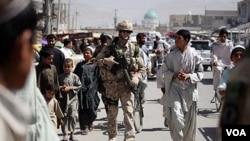 Tentara NATO berbincang dengan warga setempat di kota Kandahar.