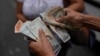 ARCHIVO - Un trabajador del servicio de transporte de Caracas cuenta bolívares y dólares estadounidenses, el 9 de agosto de 2023.