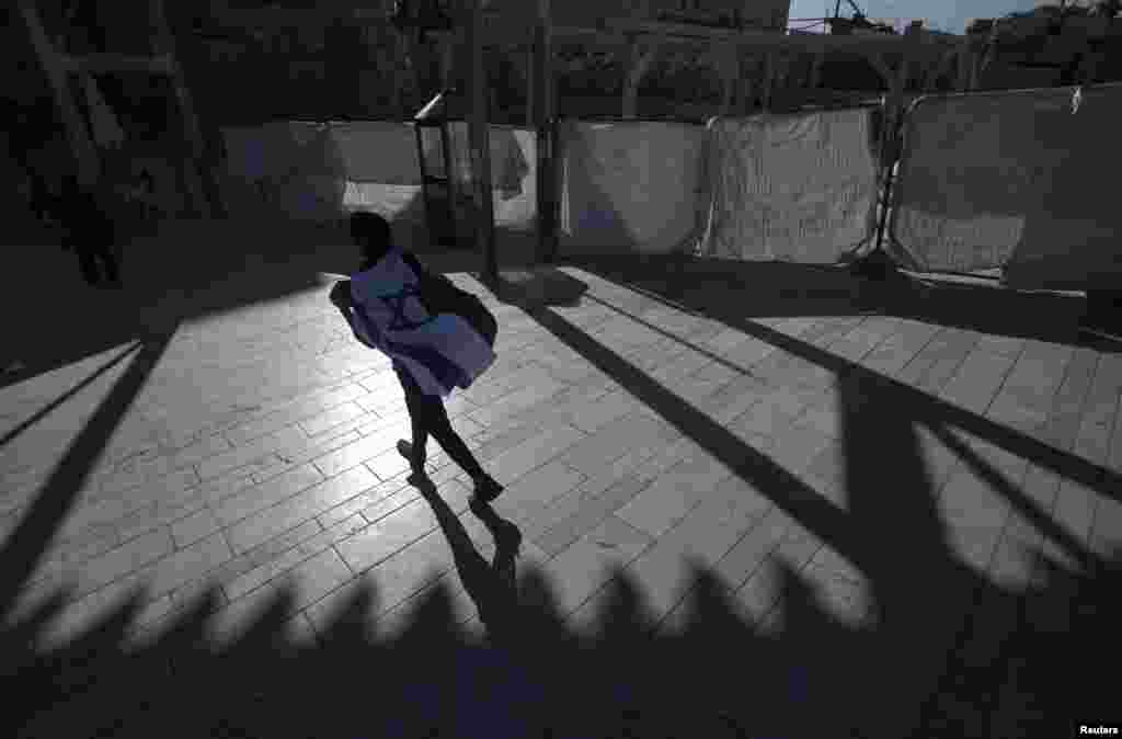 A visitor wrapped with Israel's national flag walks towards the Western Wall, Judaism's holiest prayer site, in Jerusalem's Old City.