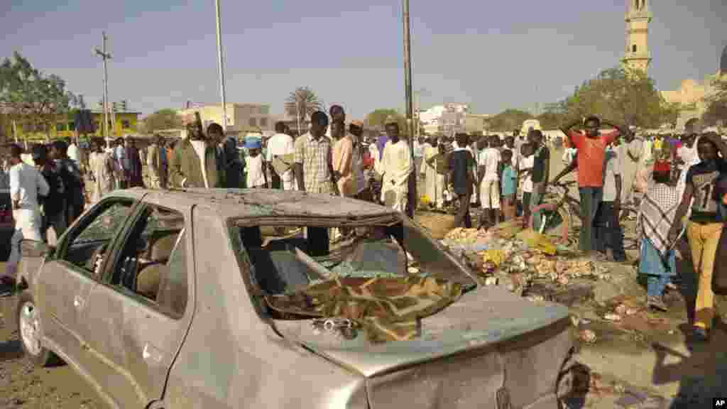 Mutane sun taru su na kallo a inda bam ya tashi a babban Masallacin Jumma'a na Kano, Jumma'a 28 Nuwamba, 2014. Mutane da yawa sun rasa rayukansu, kuma jami'ai suka ce watakila yawan wadanda zasu hallaka zai karu.