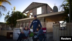 Reynaldo Gonzalez, center, nephew of 73 year-old Nelson Martinez, who died after a wall collapsed during an earthquake, waits with family members for Martinez's body to be removed in Ponce, Puerto Rico, Tuesday, Jan. 7, 2020. 