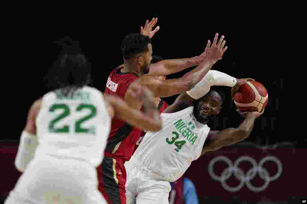 Nigeria's Ike Nwamu (34), right, is blocked by Germany's Johannes Thiemann (32), center, during men's basketball preliminary round game at the 2020 Summer Olympics, Wednesday, July 28, 2021, in Saitama, Japan. (AP Photo/Eric Gay)