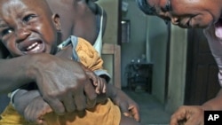 Aliyatu Abdulai (R), a Maternal and Child Health Aide, administers a vaccine to a child in the village of Sembehun, Sierra Leone, which is supported by the GAVI Alliance that funds vaccine programs, May 23, 2011