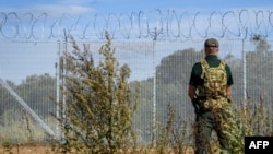 Stražar stoji pored granične ograde sa bodljikavom žicom na granici Letonije sa Rusijom, 16. august, 2024. (Foto: AFP/Gints Ivuskans)
