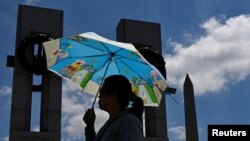 资料照片：一名妇女在高温中参观华盛顿二战纪念碑。(2024年6月19日)