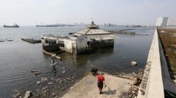 People walk near a giant sea wall that prevents sea water from flowing into Jakarta, Indonesia, July 27, 2019.