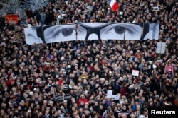 FILE - People hold panels to create the eyes of late Charlie Hebdo editor Stephane Charbonnier, known as "Charb", as hundreds of thousands of French citizens take part in a solidarity march in the streets of Paris, Jan. 11, 2015.