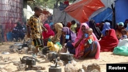 FILE - Somali families, displaced after fleeing the Lower Shabelle region amid an uptick in U.S. airstrikes, wait at an IDP (internally displaced person) camp near Mogadishu, Somalia, on March 12, 2020.