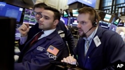 El corredor de bolsa Michael Milano, derecha, trabaja con los especialistas Karan Virdi, centro y David Haubner, izquierda, en la Bolsa de Valores de Nueva York, el martes 9 de enero de 2018.