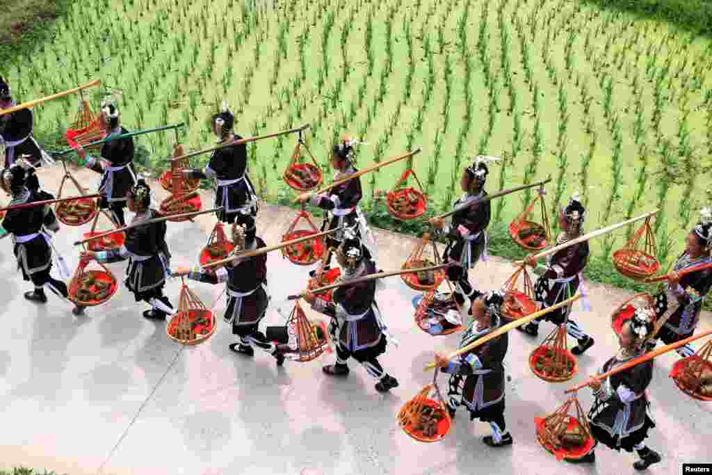 Wanita suku minoritas Dong membawa paket “zongzi,” atau ketan, selama festival lokal di desa di Kabupaten Liping, Provinsi Guizhou, China, 17 Juni 2017.