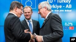 Le Premier ministre turc, Ahmet Davutoglu, à gauche, parle avec Jean-Claude Juncker, président de la Commission européenne, à droite, et Donald Tusk, président du Conseil européen, au centre, après une conférence de presse lors d'un sommet européen à Bruxelles, en Belgique, 8 mars 2016.