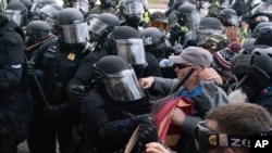 Maafisa wa polisi wa Bunge la Marekani wakiwazuia waandamanaji wanaojaribu kuvunja mlango wa Bunge Jumatano, Jan. 6, 2021, in Washington. (AP Photo/Jose Luis Magana)