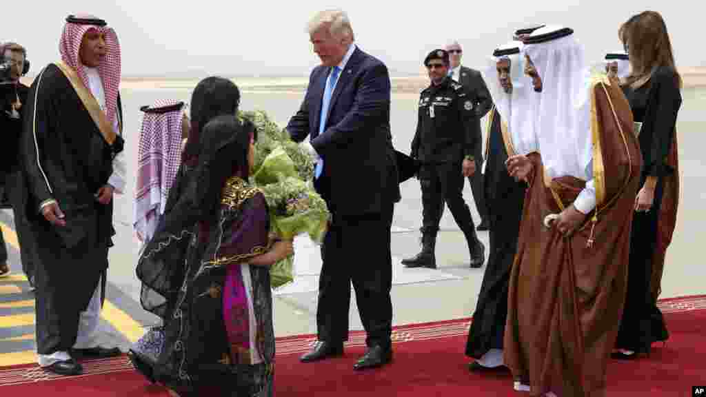 Le président Donald Trump, au centre, reçoit un bouquet de fleurs de bienvenue aux côtés du roi saoudien Salman à l’aéroport international roi Khalid, Ryad 20 mai 2017.