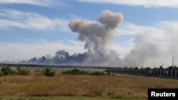 Asap tampak mengepul dari lokasi pangkalan udara pasukan militer Rusia di dekat Novofedorivka, Krimea, sesaat setelah ledakan terdengar dari lokasi tersebut pada 9 Agustus 2022. (Foto: Reuters)