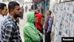 Sejumlah warga membaca koran yang tertempel di dinding di sebuah area di Dhaka, sehari setelah pemilu berlangsung di Bangladesh pada 8 Januari 2024. (Foto: Reuters/Mohammad Ponir Hossain)
