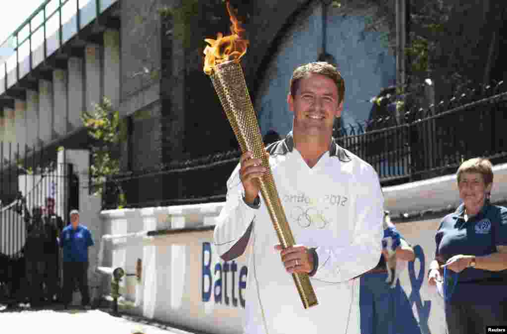 Former England striker Michael Owen poses with the Olympic Torch at Battersea dogs home in London, July 23, 2012.