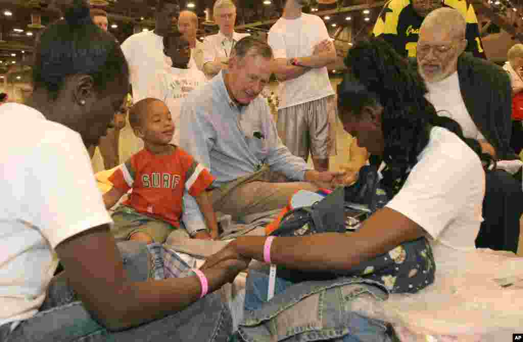 L'ancien président George H. W. Bush prie avec des vicitimes de l'ouragan, Katrina Rebecca Solomon, à gauche, Terrill Hoskins, 3ème, LaShonda Hoskins et Ernie Ladd dans le Reliant Center adjacent à l'Astrodome de Houston, lundi 5 septembre 2005.