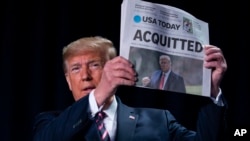 Le président Donald Trump exhibe la une du quotidien USA Today, avec en titre "ACQUITTÉ", le 6 février 2020 à Washington.